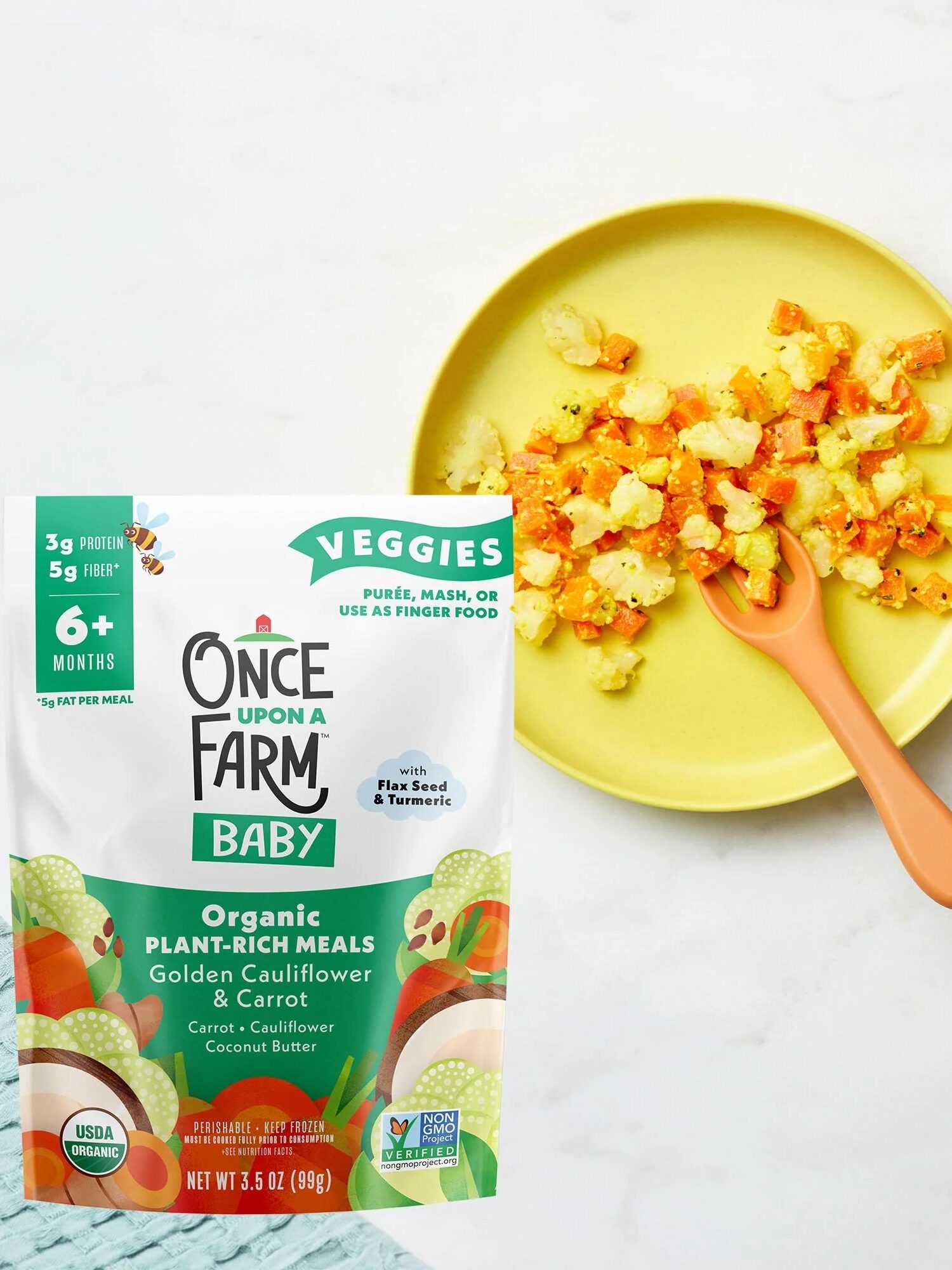 A package of "Once Upon a Farm Baby Organic Plant-Rich Meals" next to a yellow plate with mashed golden cauliflower and carrots and an orange spoon.