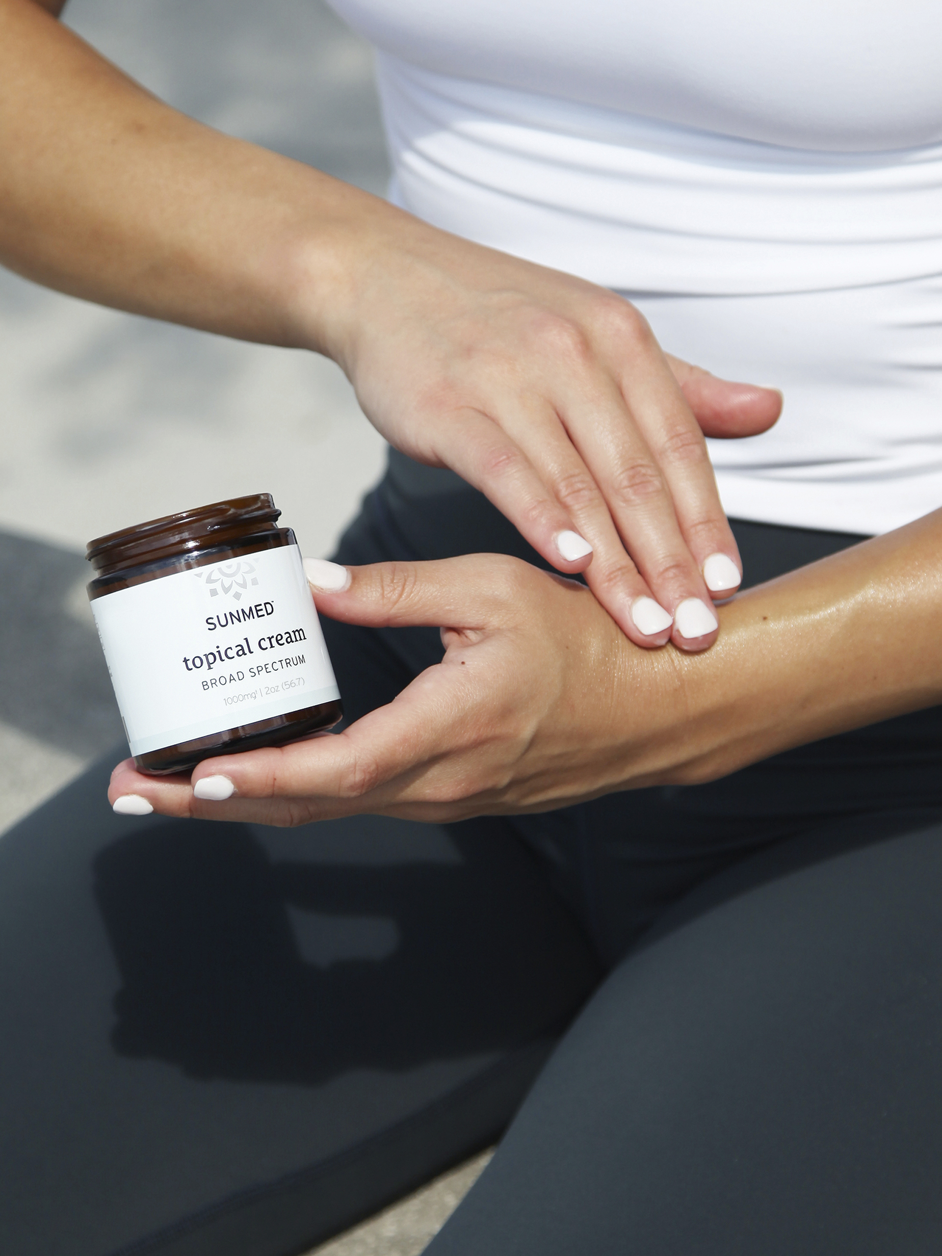 A person applies SunMed topical cream on their arm.