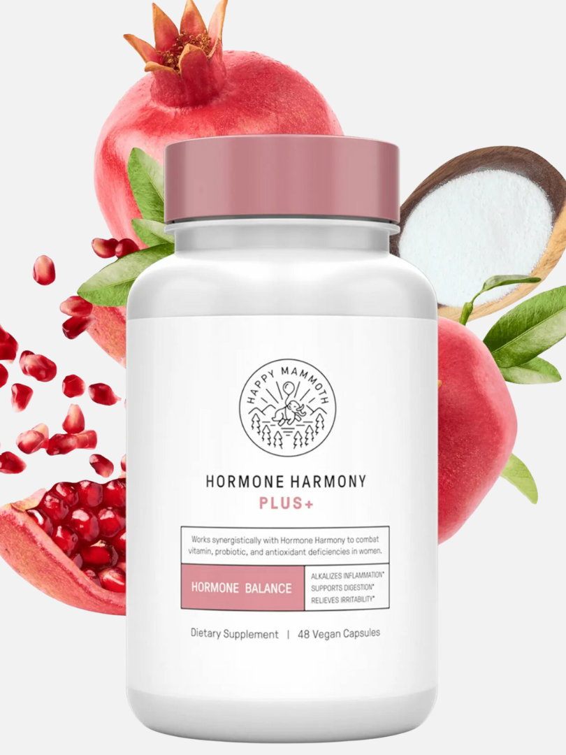 A white bottle labeled "Hormone Harmony Plus+" by Happy Mammoth is displayed with pomegranate, coconut, and seeds around it. The bottle contains 48 vegan capsules for hormone balance.