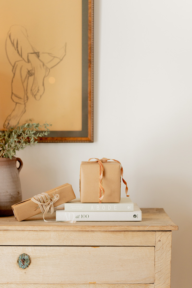 A stack of gifts on a table, next to a plant.