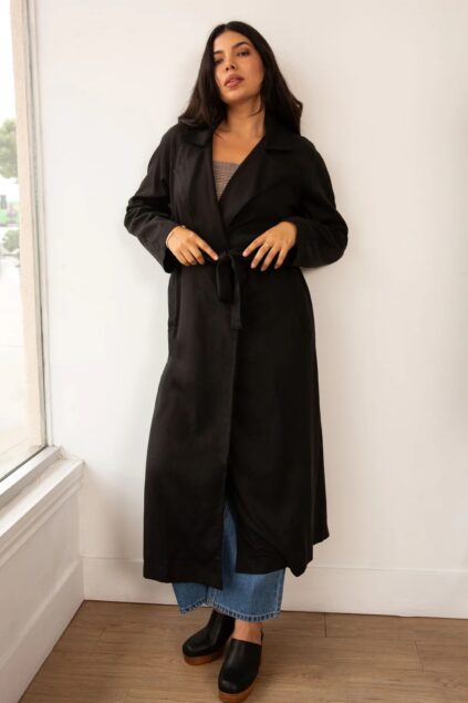 A model wearing a long black pea coat from Whimsy + Row.