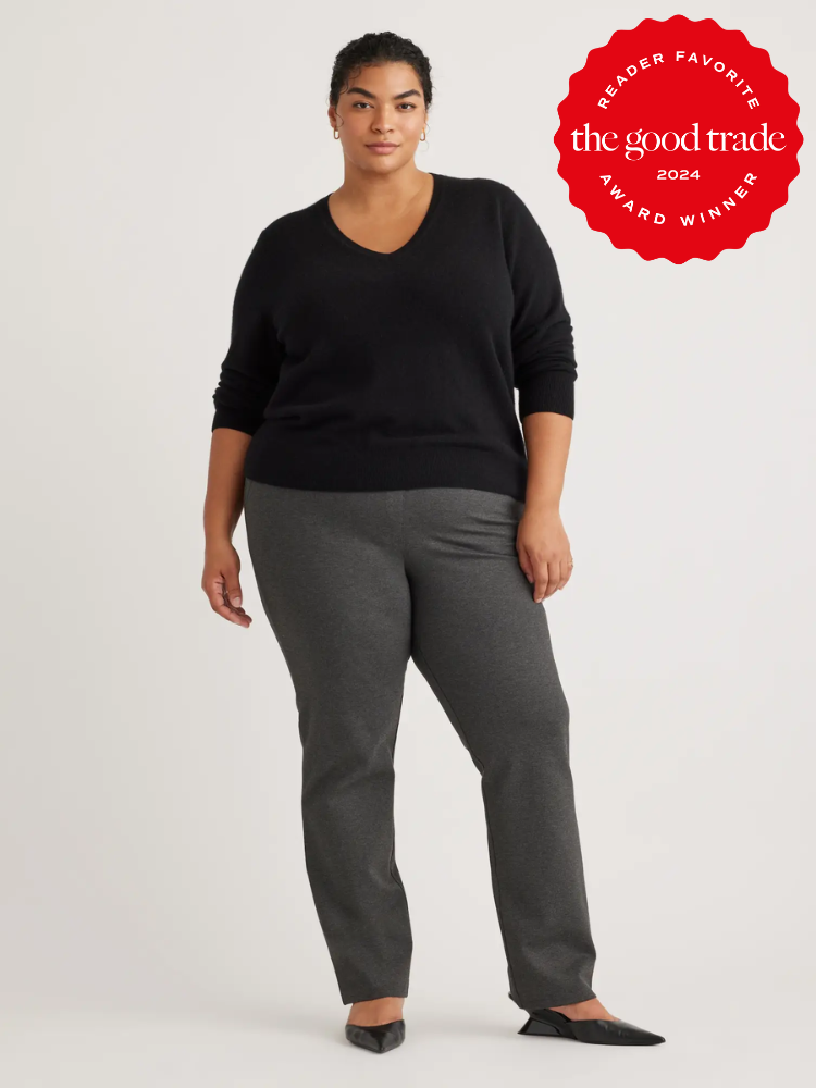 A plus size model wearing a black v neck sweater and grey trousers from Quince. 