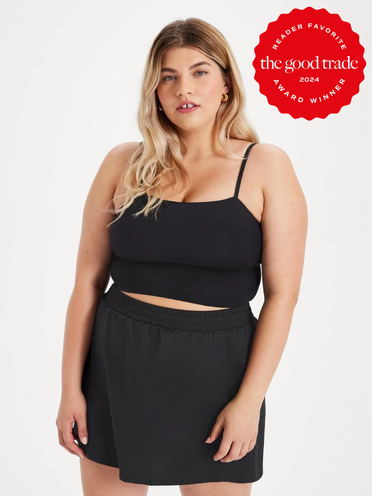 A plus size model wearing a black tank top and black skirt from Girlfriend Collective. 