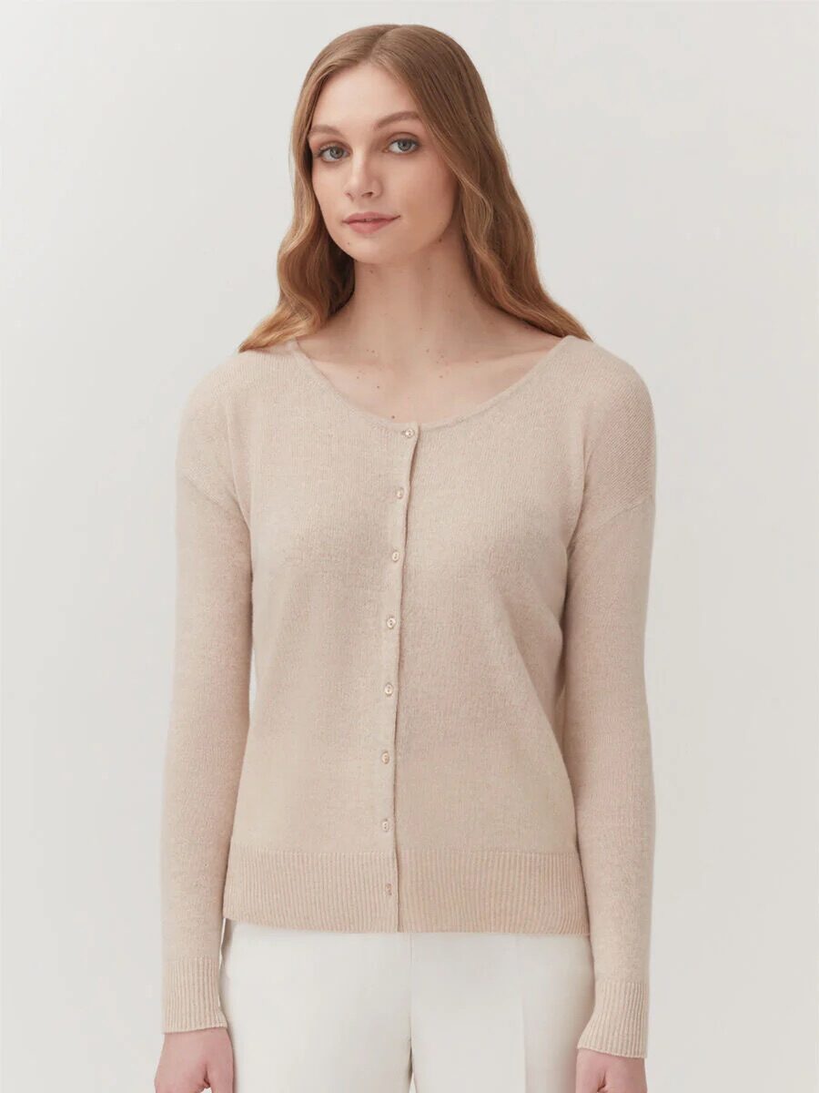 A model wearing a beige button-up cardigan from Cuyana. 