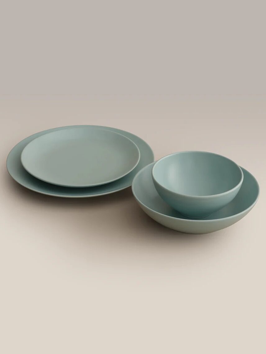 A set of light blue dinnerware including two plates, one bowl, and one larger bowl arranged neatly on a neutral background.