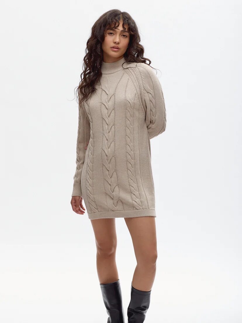 A model wearing a cable-knit turtleneck sweater dress from Kotn. 