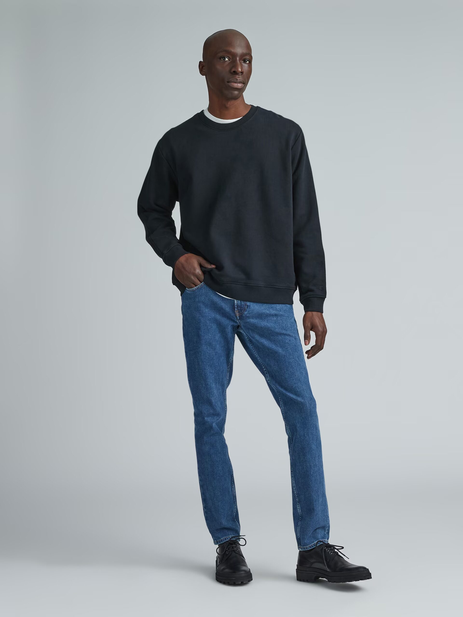 A model wearing Everlane medium wash jeans.