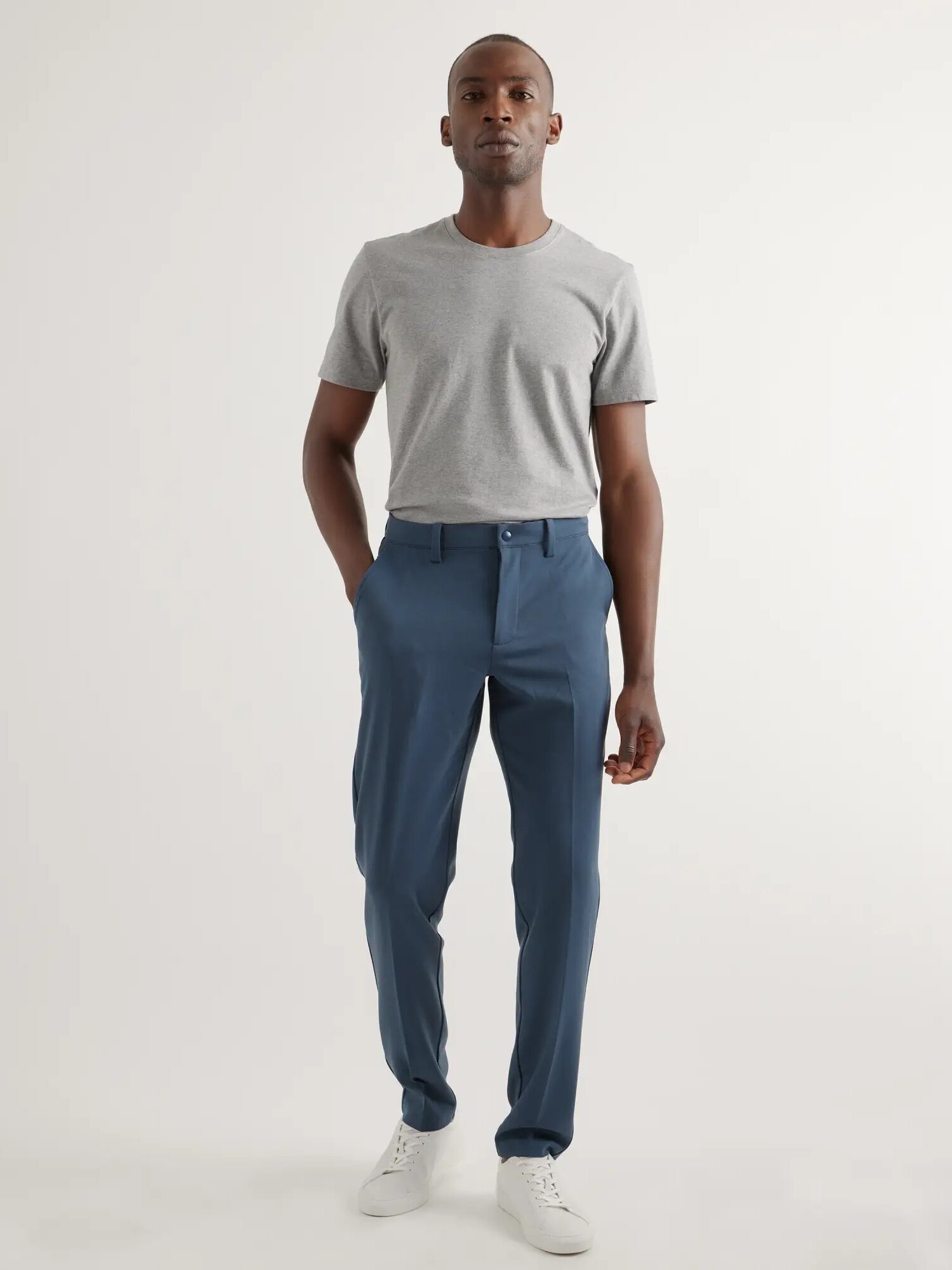 A model wearing blue chino pants from Quince. 