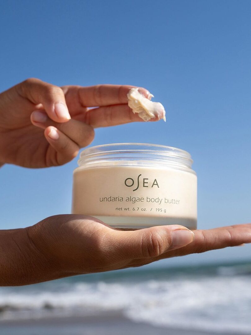 A hand dipped into a jar of OSEA's Body Butter.