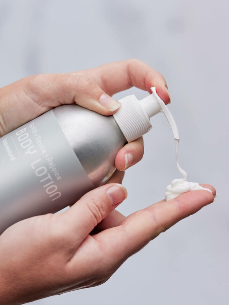 A close up of a Plaine Products Body Lotion being pumped onto a finger. 