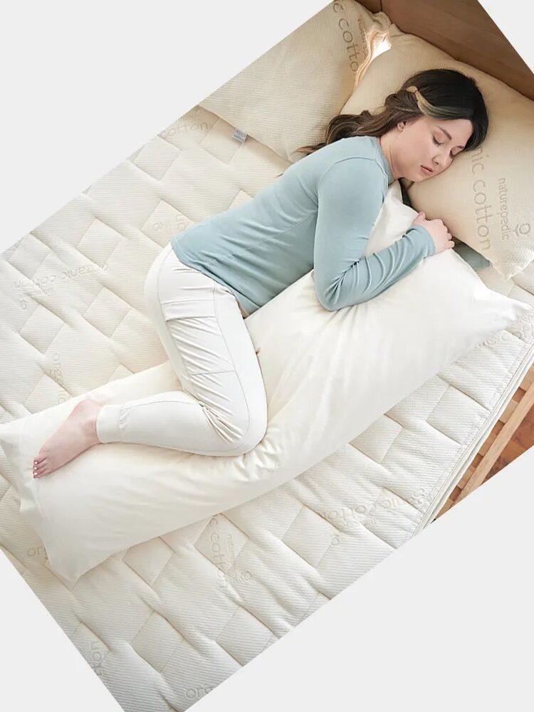 A model sleeping on a Naturepedic body pillow. 