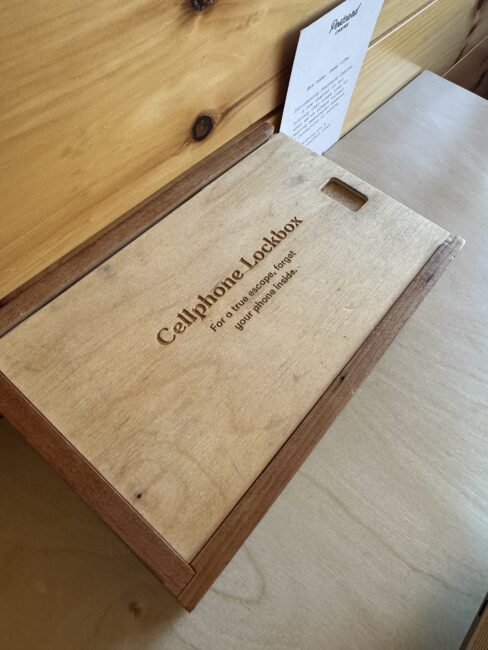 Wooden cell phone lockbox with a lid, engraved with "Cellphone Lockbox" and a message encouraging phone-free relaxation.