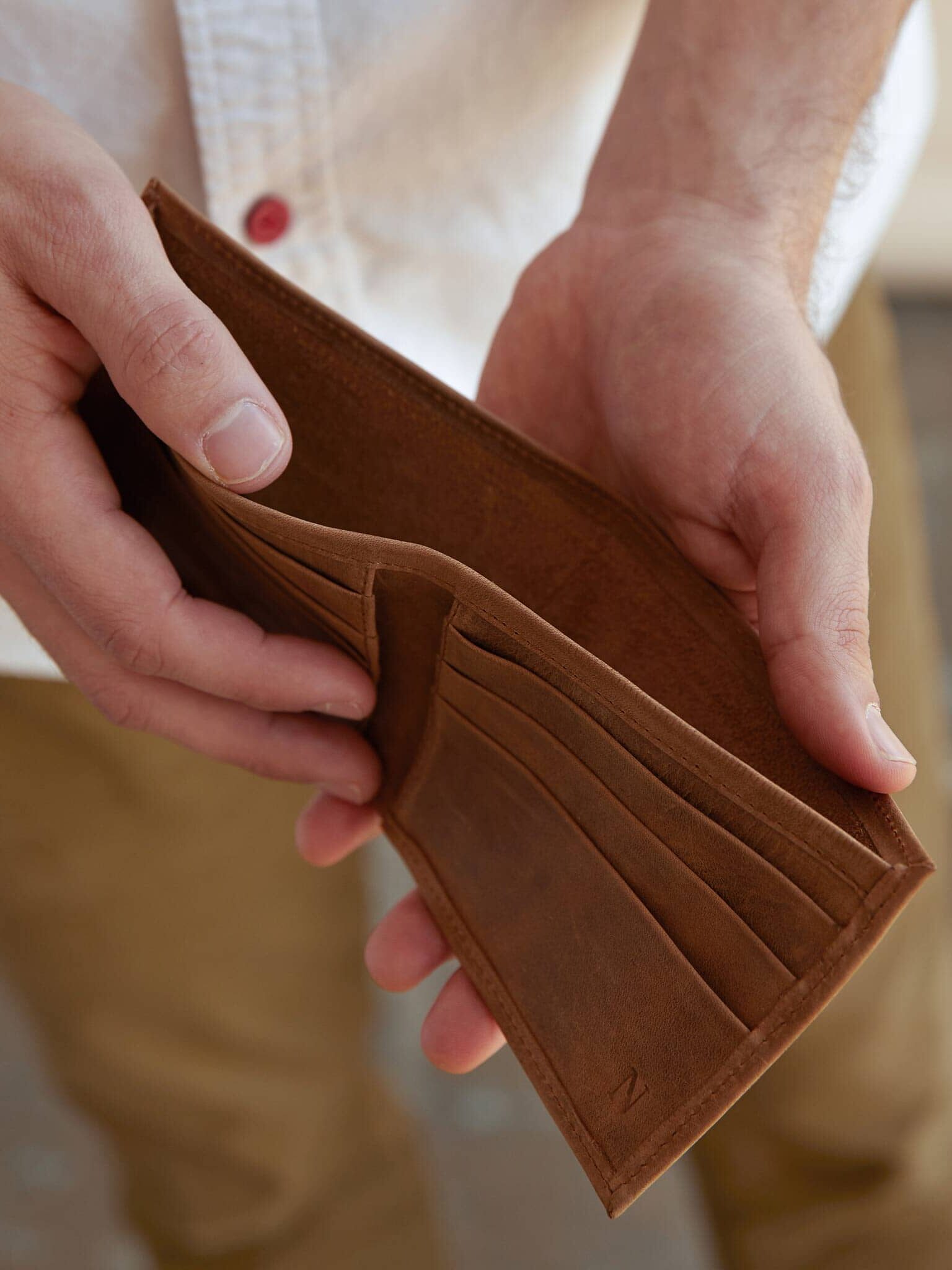 A close up of a pair of hands opening a Nisolo wallet.