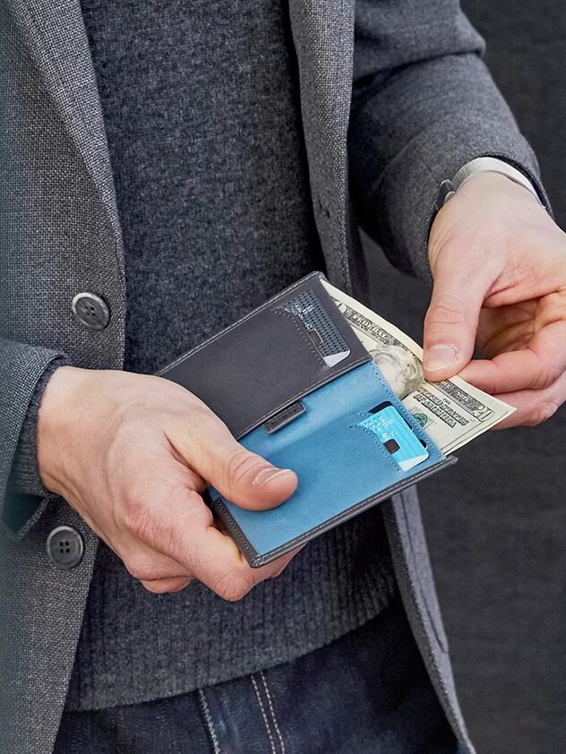 A close up of a model pulling our cash from a Bellroy wallet. 