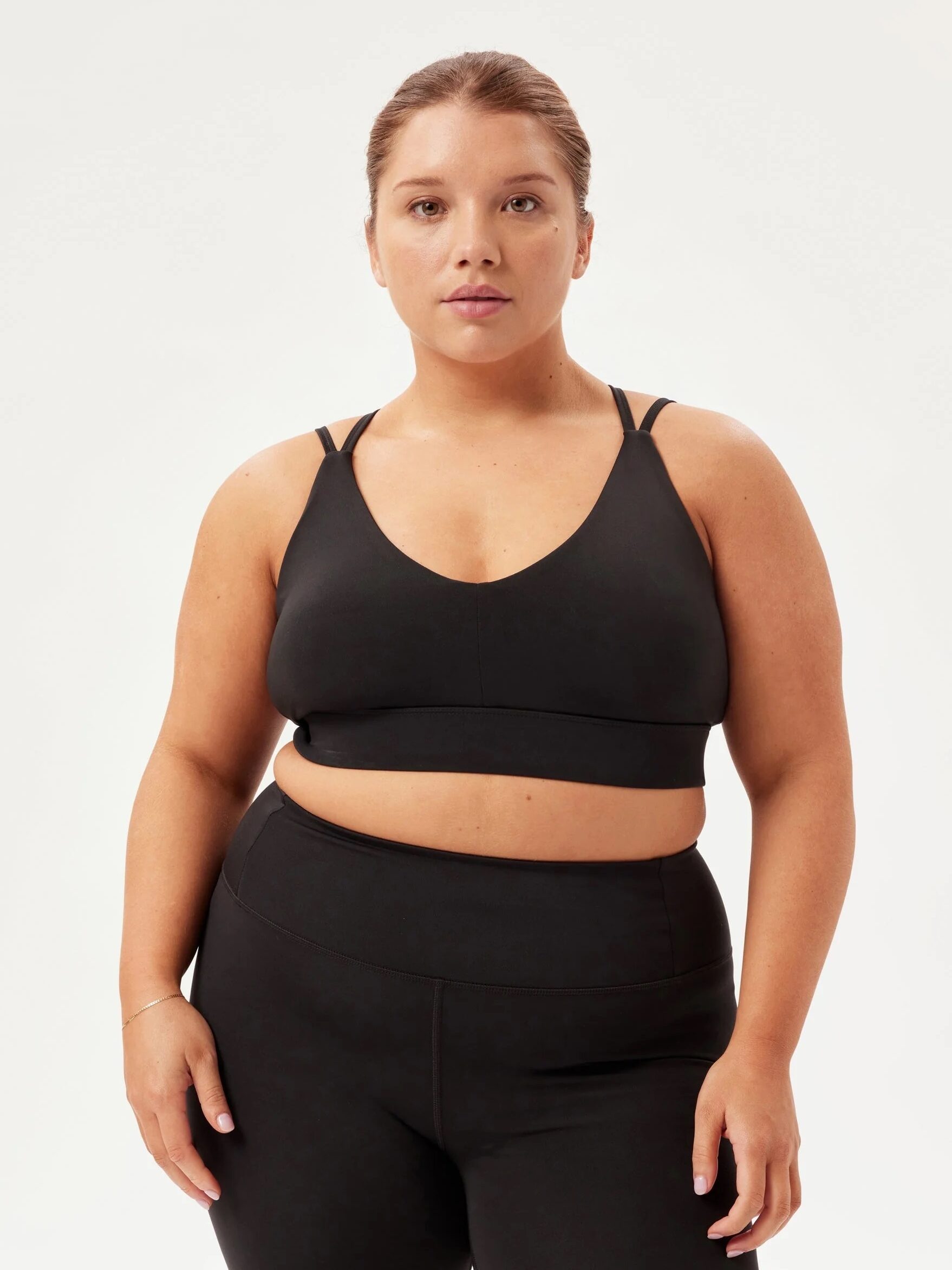 A person stands facing forward, wearing a black sports bra and black high-waisted athletic shorts.