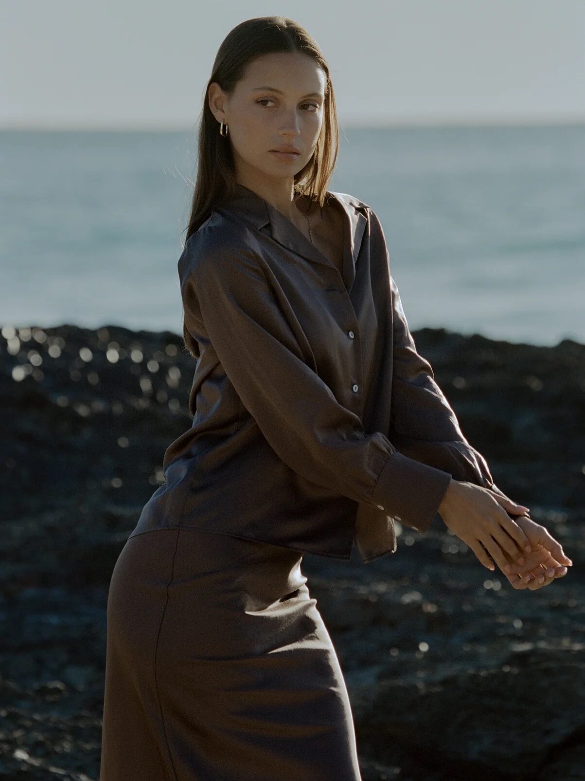 A model posing in front of the edge of a cliff, wearing Petite Femme clothing.