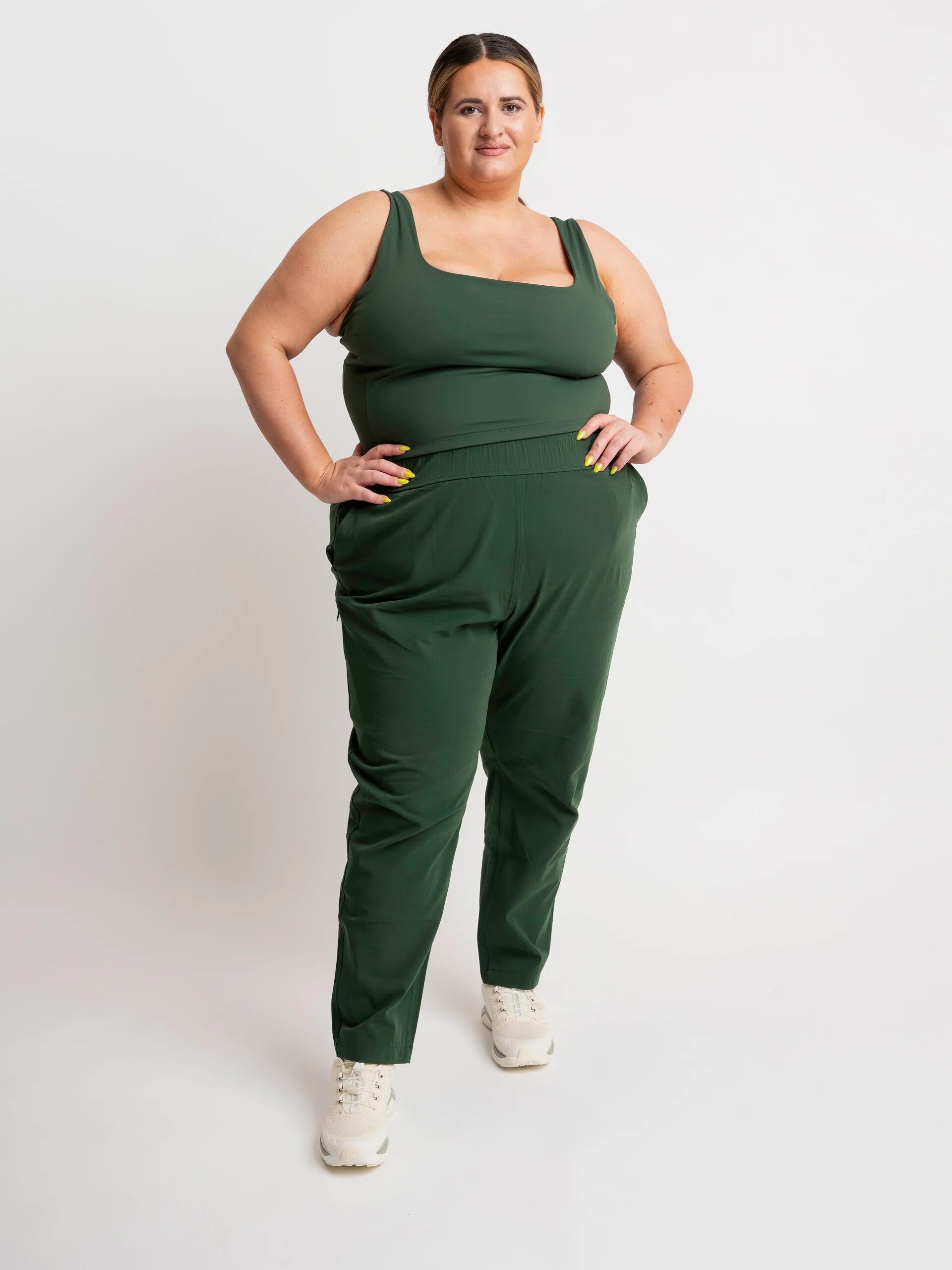 A plus size model wearing a matching green athleisure set from alder apparel. 