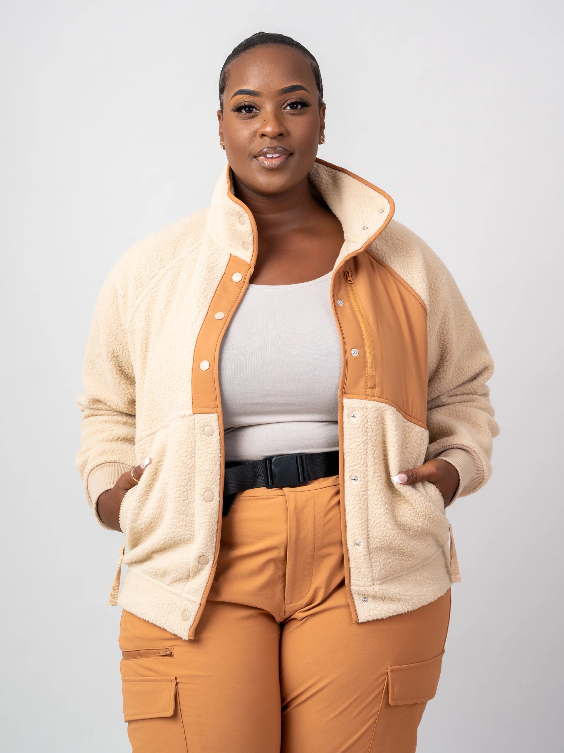 A plus size model wearing a yellow and cream fuzzy jacket and yellow cargo pants from alder apparel. 