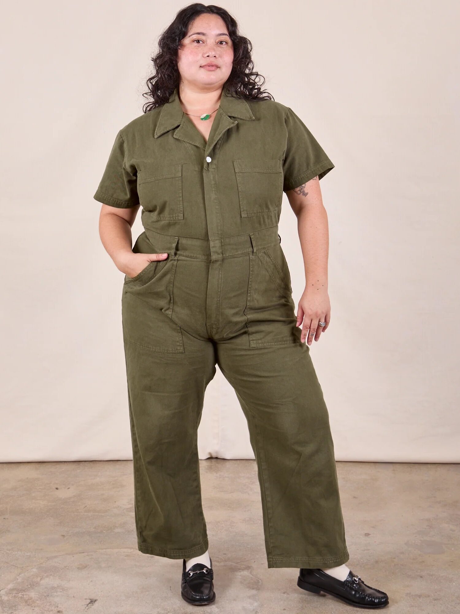 A plus size model wearing an army-green jumpsuit from Big Bud Press. 