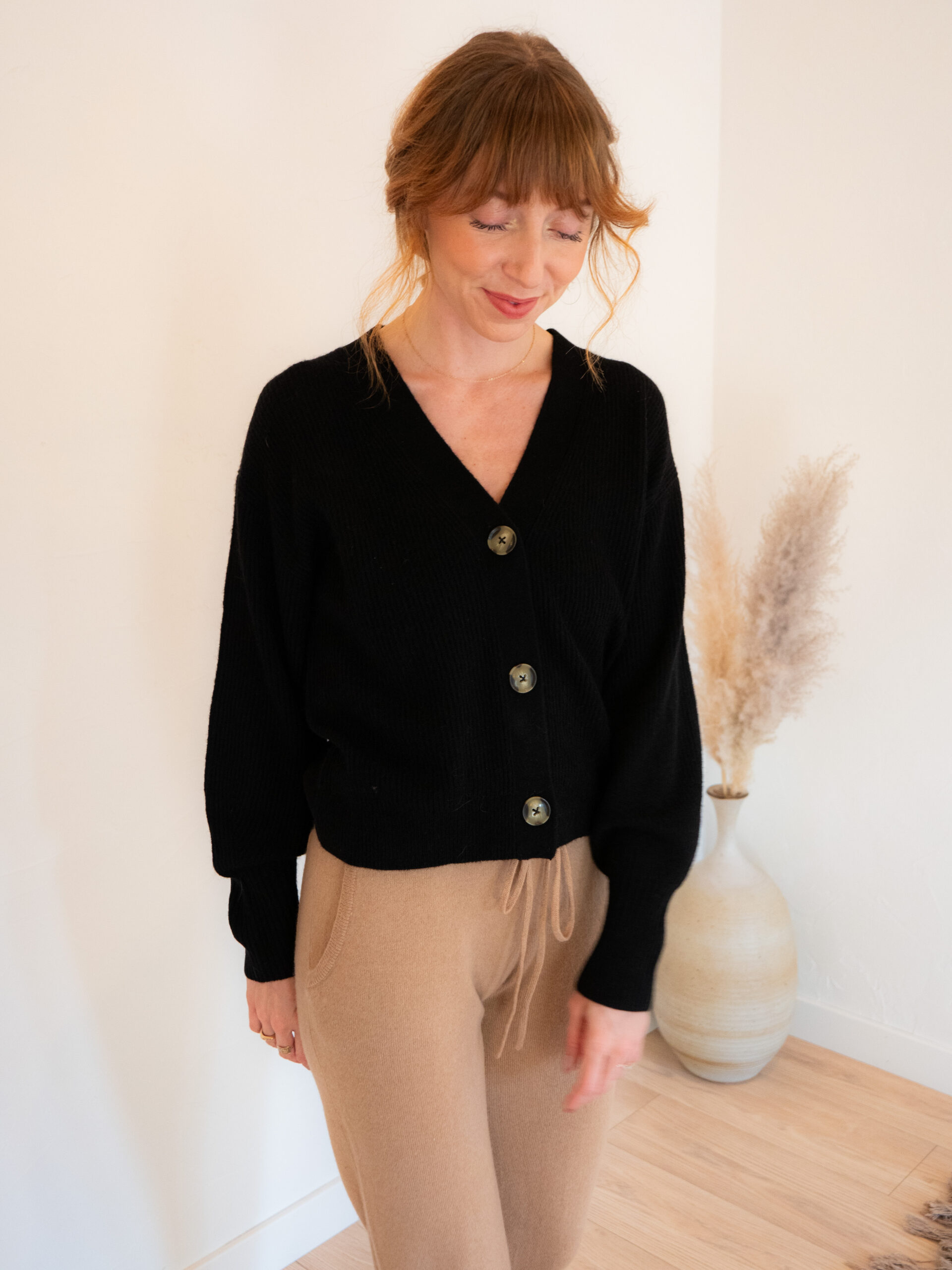 Courtney Jay Higgens, Contributing Editor at The Good Trade, wears a V-neck button-up cardigan in black from Quince. 