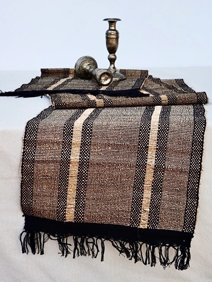 A woven black, brown, and yellow striped table runner from Terraklay. 