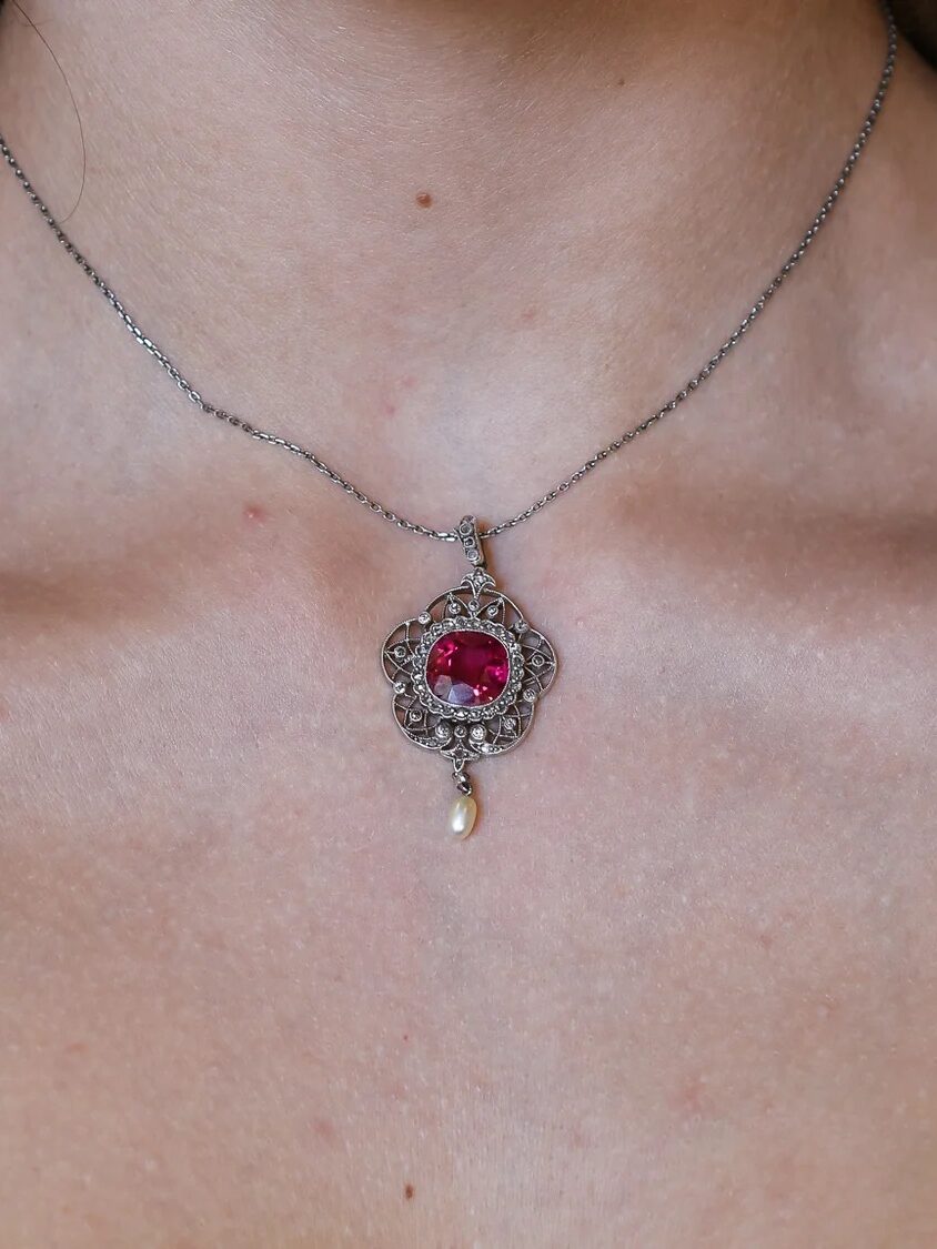 A vintage pendant necklace with a magenta stone in the center. 