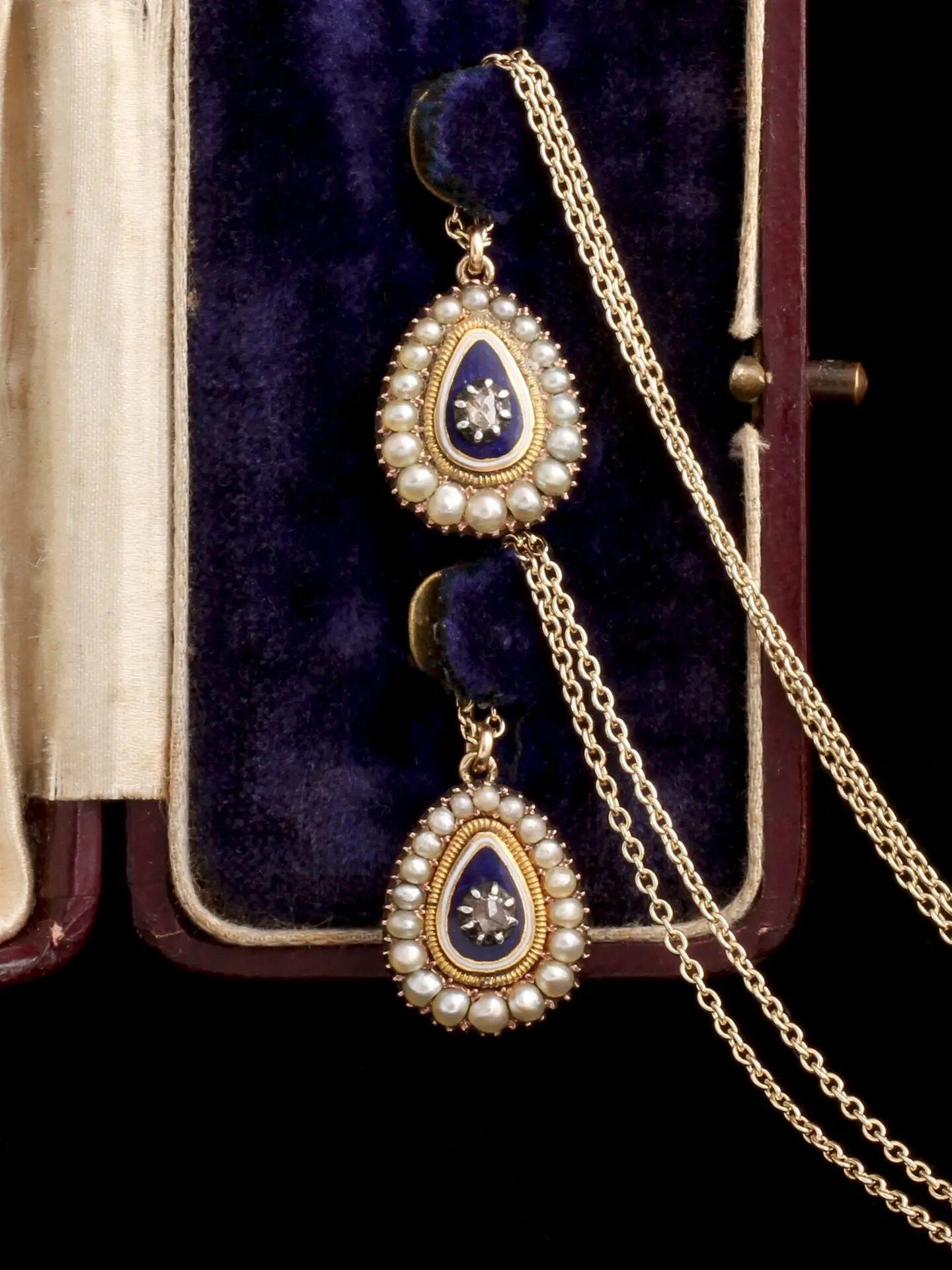 Two pendant necklaces in a jewelry box. 