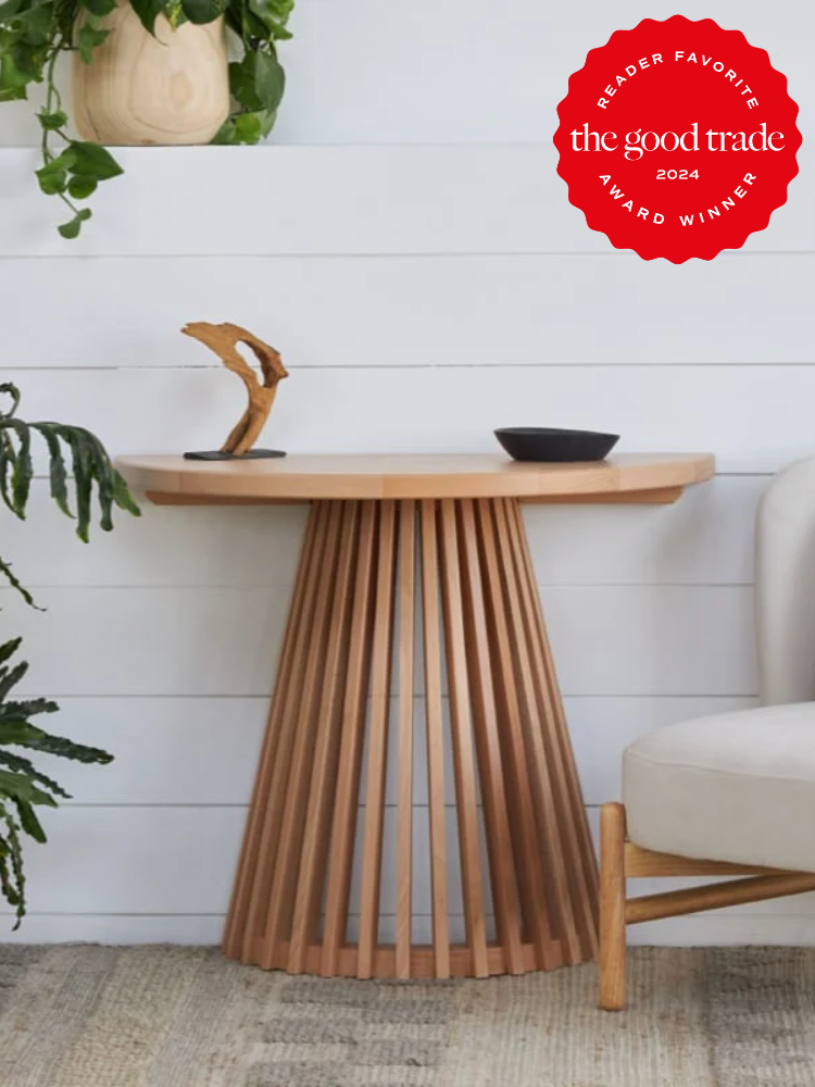 A wooden accent table with a fluted base is displayed next to a plant and chair, featuring a decorative sculpture and small bowl on top. A "Reader Favorite" badge is in the upper right corner.