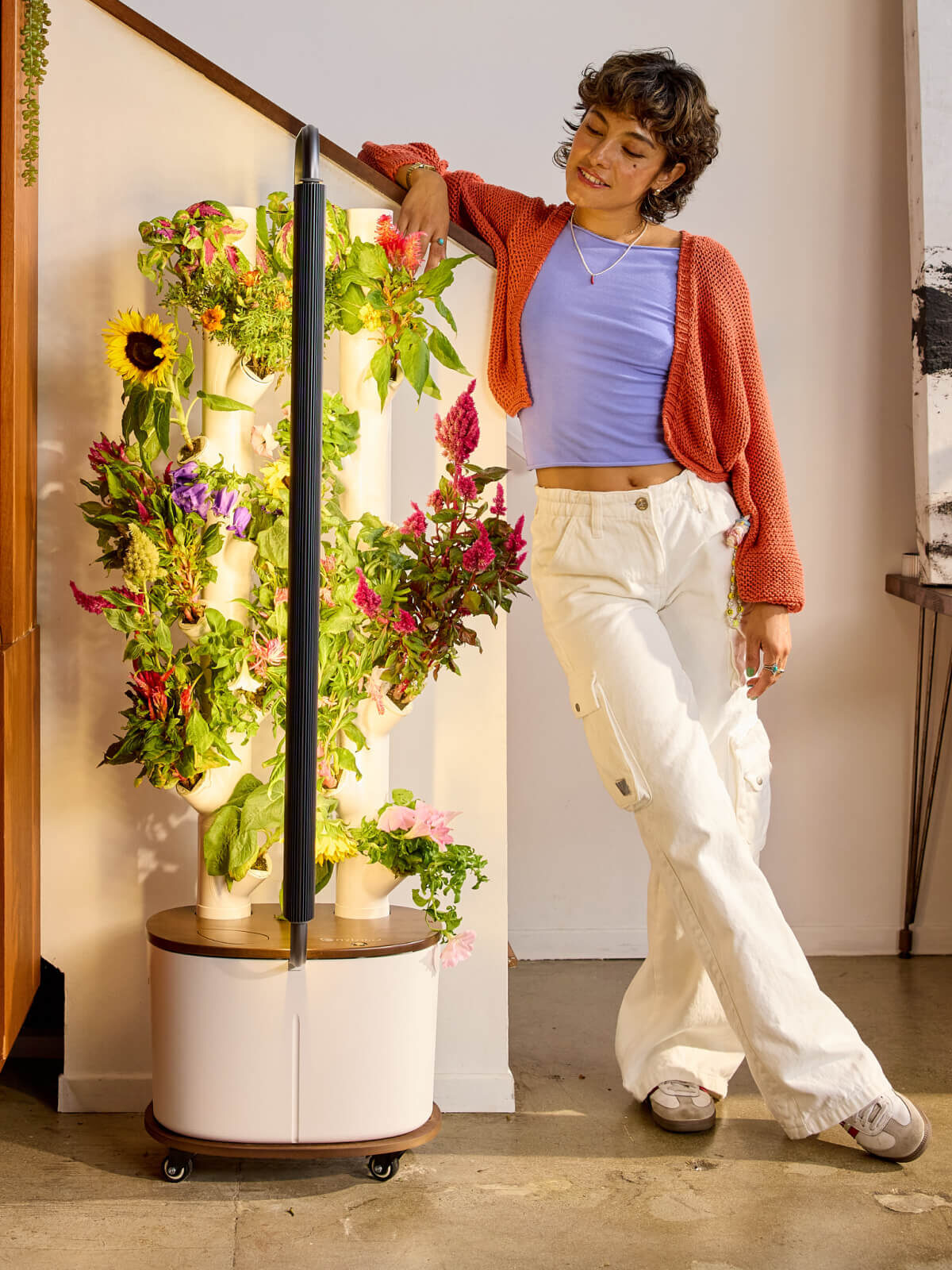 A model leaning against a Gardyn hydroponic garden. 