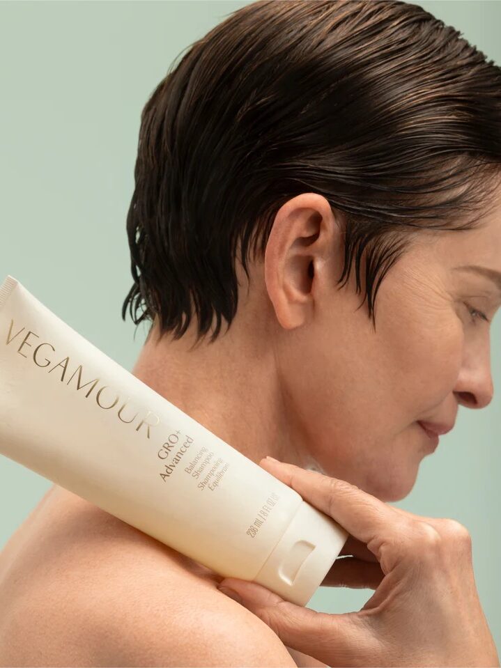 A model holding a Vegamour shampoo across their shoulder. 