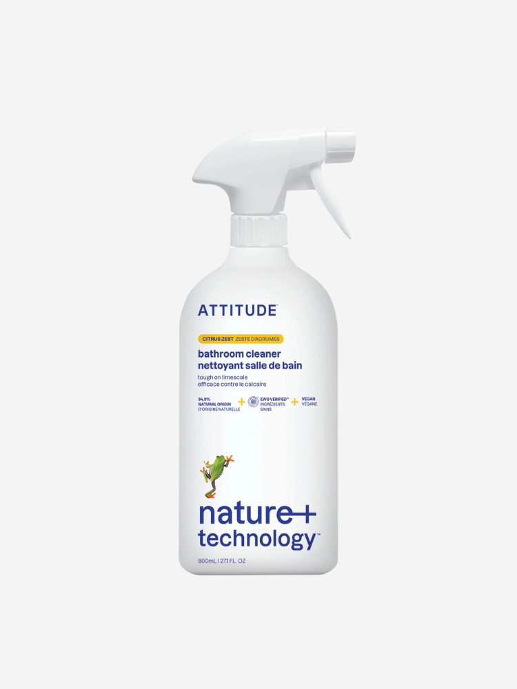 A spray bottle of Attitude bathroom cleaner with a white label and green logo, featuring the text "nature + technology" and "citrus zest scent.