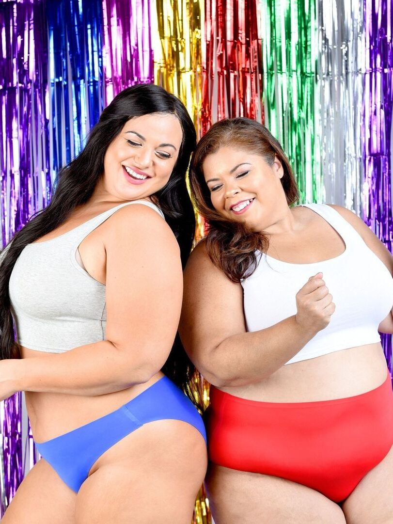 Two models laugh while bumping hips and wearing Ruby Love period underwear. 