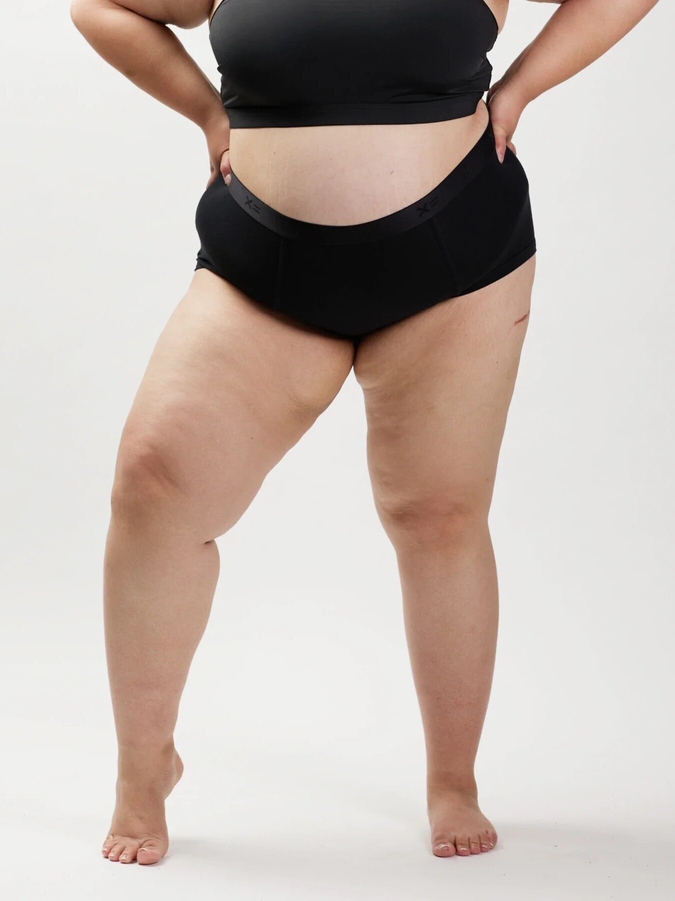 Close up of a plus size model wearing TomboyC period briefs in black. 