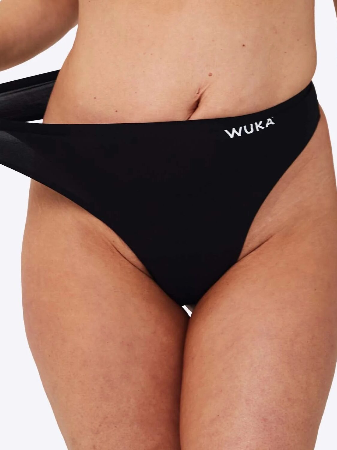 Close up of a model stretching a Wuka black period thong at the waistband. 