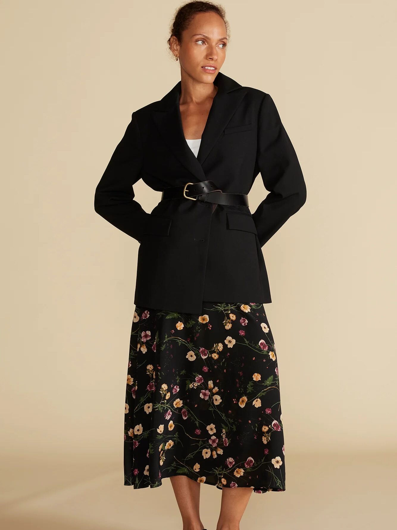 A model wearing a black silk skirt with yellow and purple florals on it, from Amour Vert. 