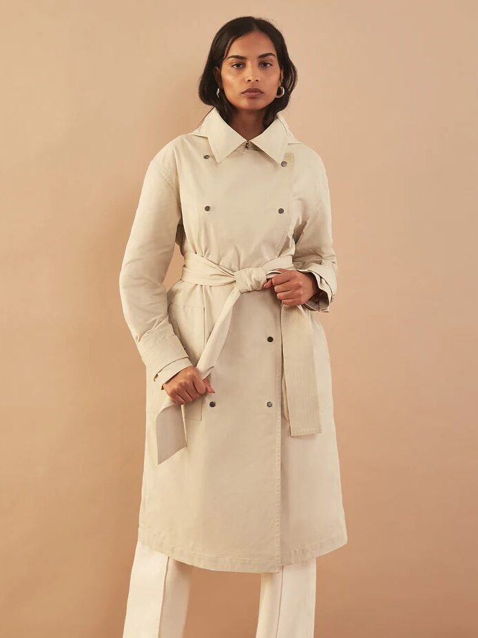 A model wearing a light beige trench from Aday. 