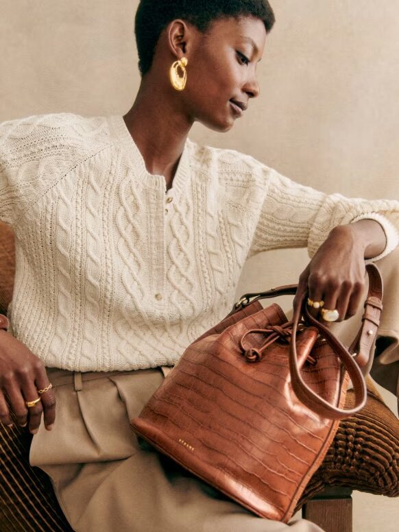 A model holding a Sezane crossbody bag. 