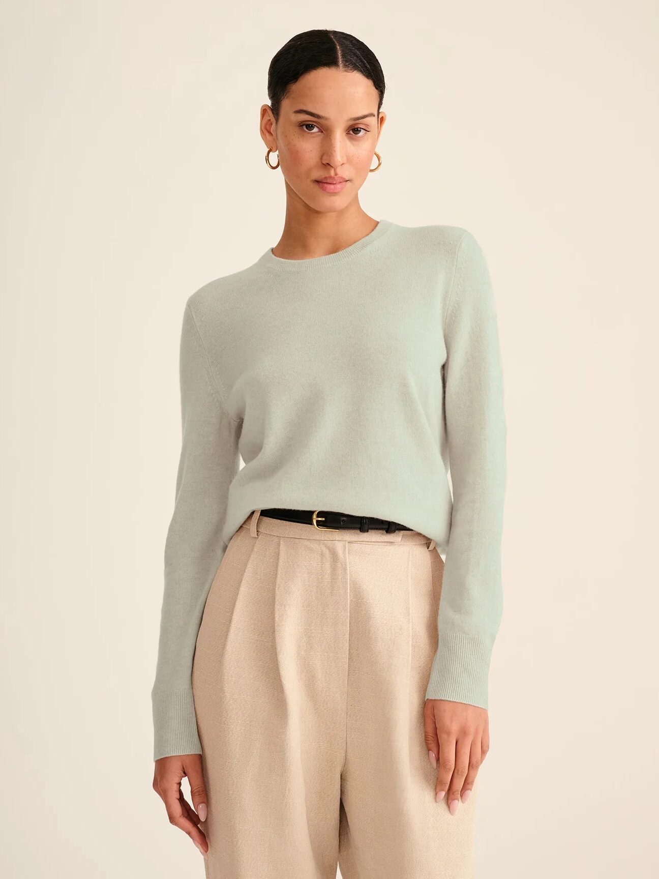 A model wearing a pale sage green NAADAM cashmere sweater. 