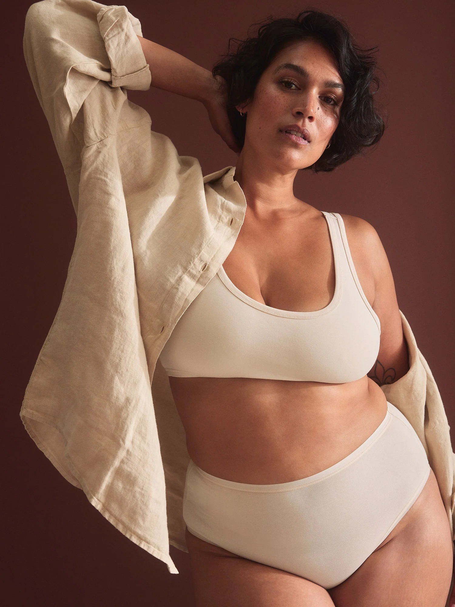 A model wearing a matching cream lingerie set with a button down shirt from MATE the Label. 