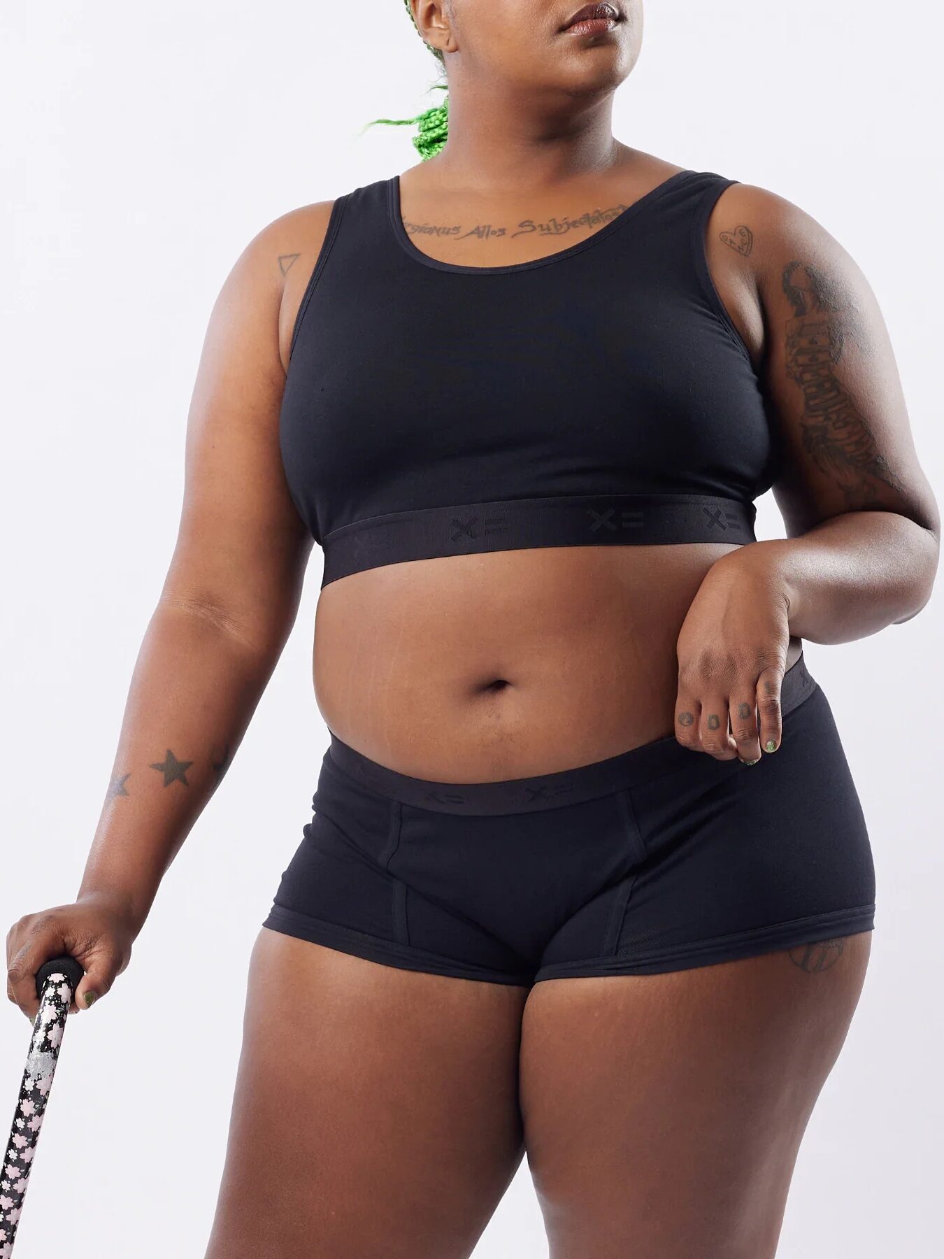 A model with a cane wearing a matching black intimates set from TomboyX. 