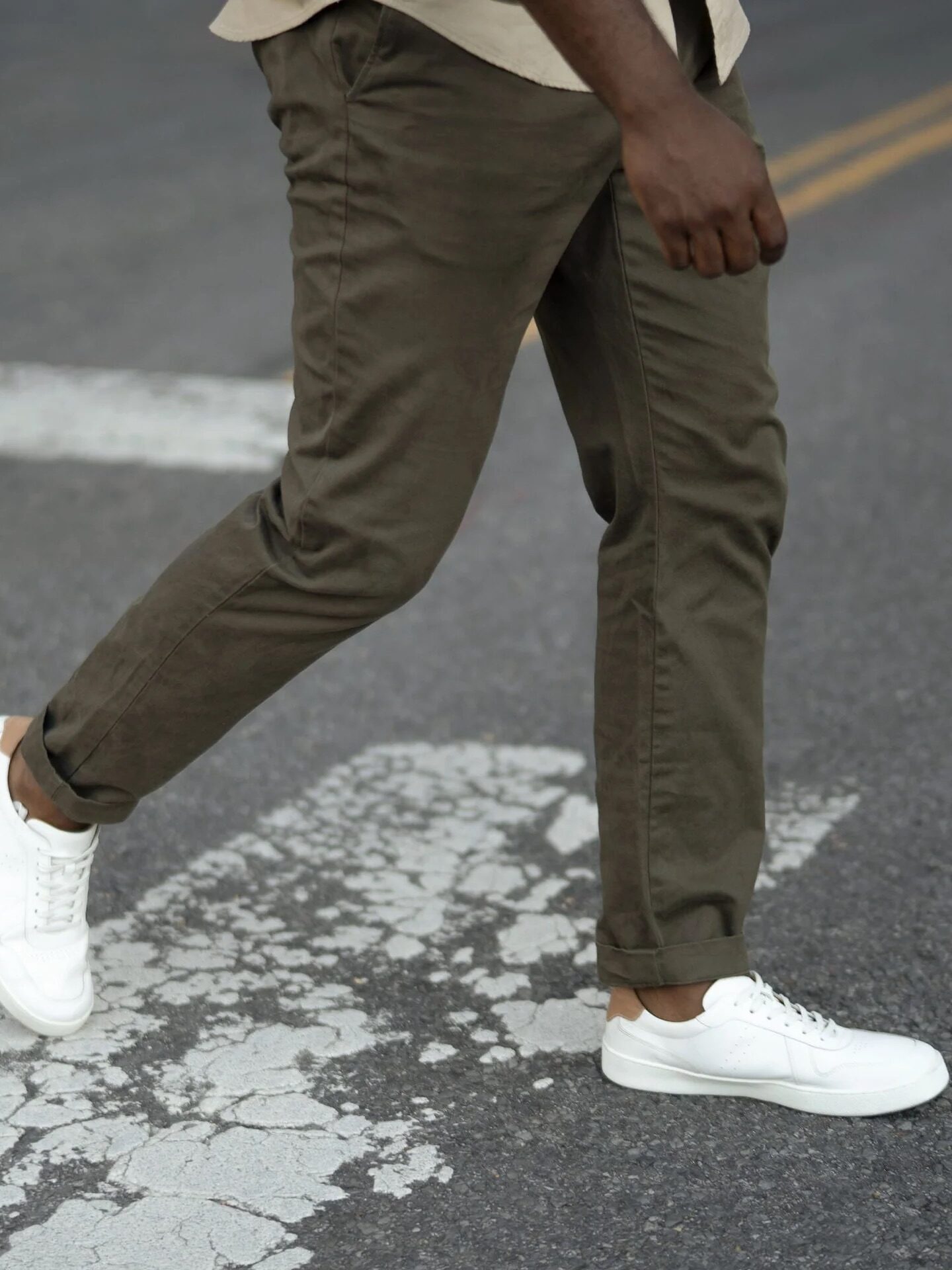 A mode walking wearing white Nisolo sneakers. 