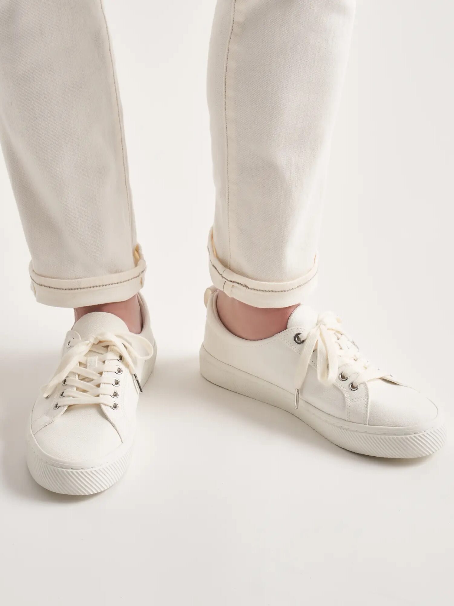 A model wearing a pair of Quince white sneakers. 