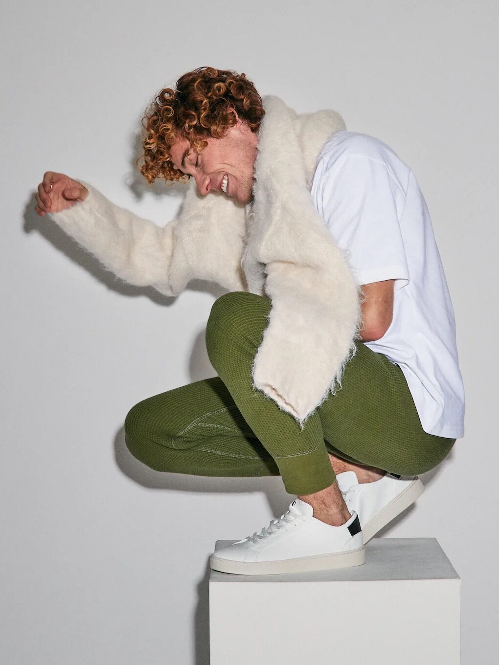 A model crouching wearing whit sneakers from Thousand Fell. 