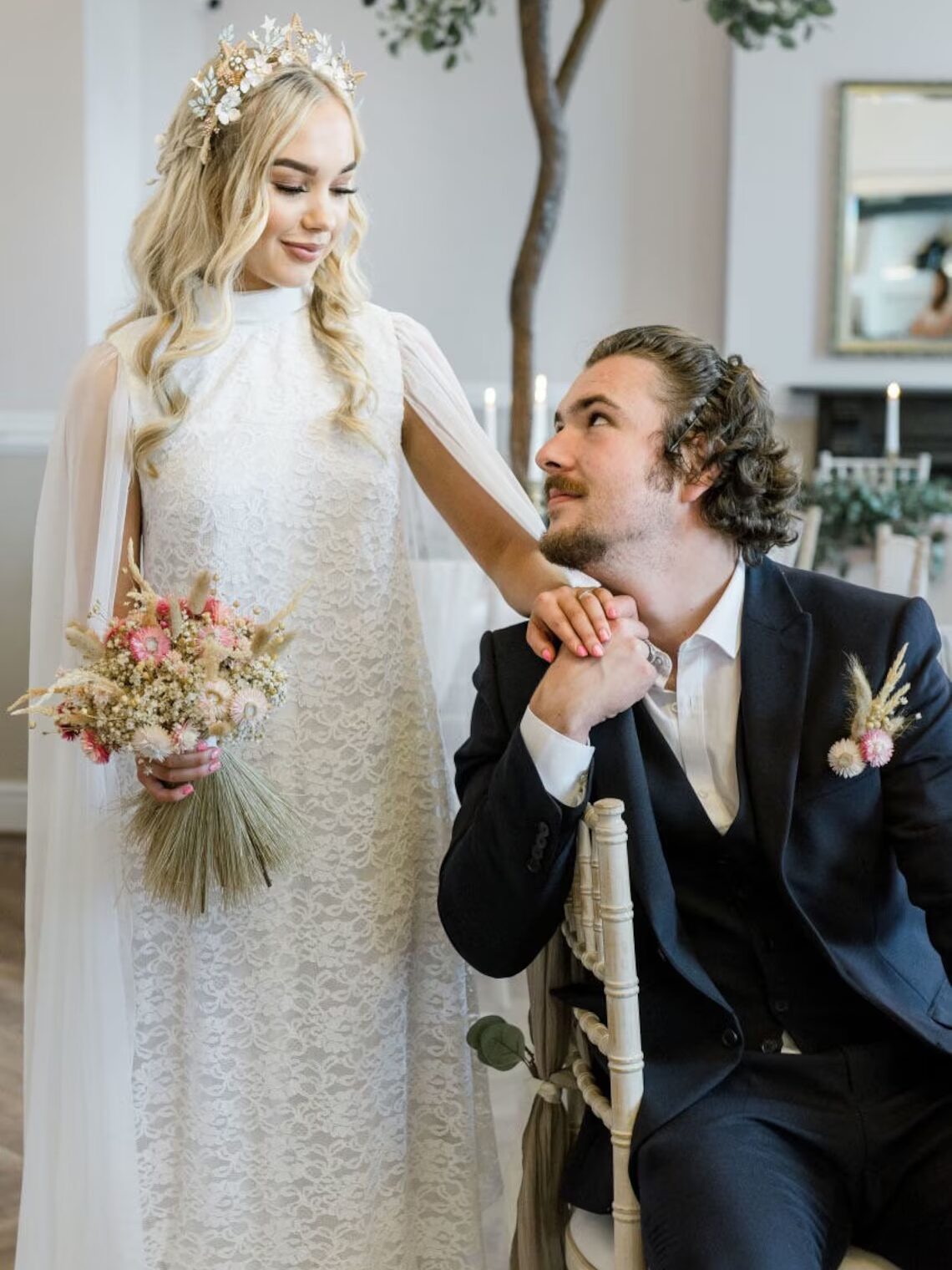 A model wearing a wedding dress from Etsy, holding a groom's hand. 