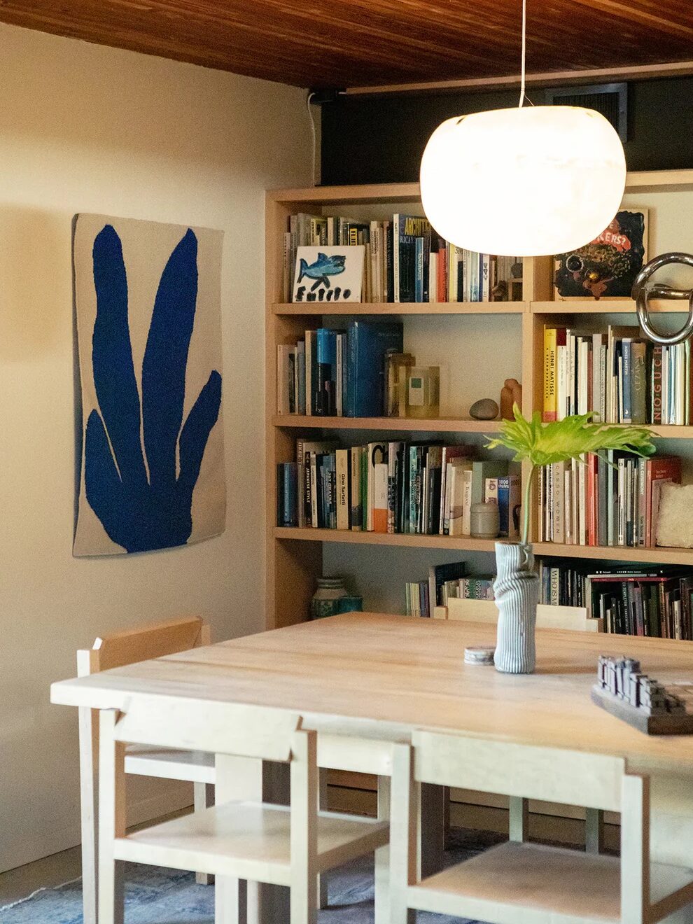 A woven abstract tapestry in blue, hanging in a library setting. 