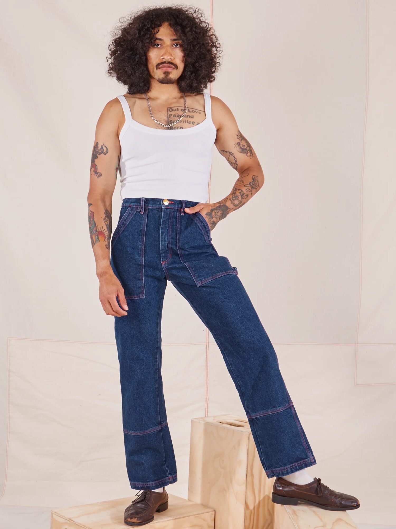 A model wearing a white tank and dark wash carpenter jeans from Big Bud Press. 