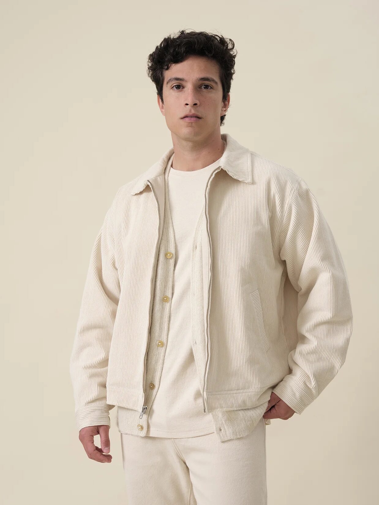 A model wearing a white corduroy jacket from Industry of all Nations. 