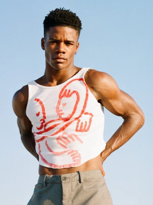 A model wearing a white tank top with an abstract red design of two people hugging on it. 