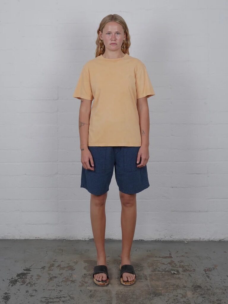 A model wearing a yellow t-shirt and navy shorts from Olderbrother. 