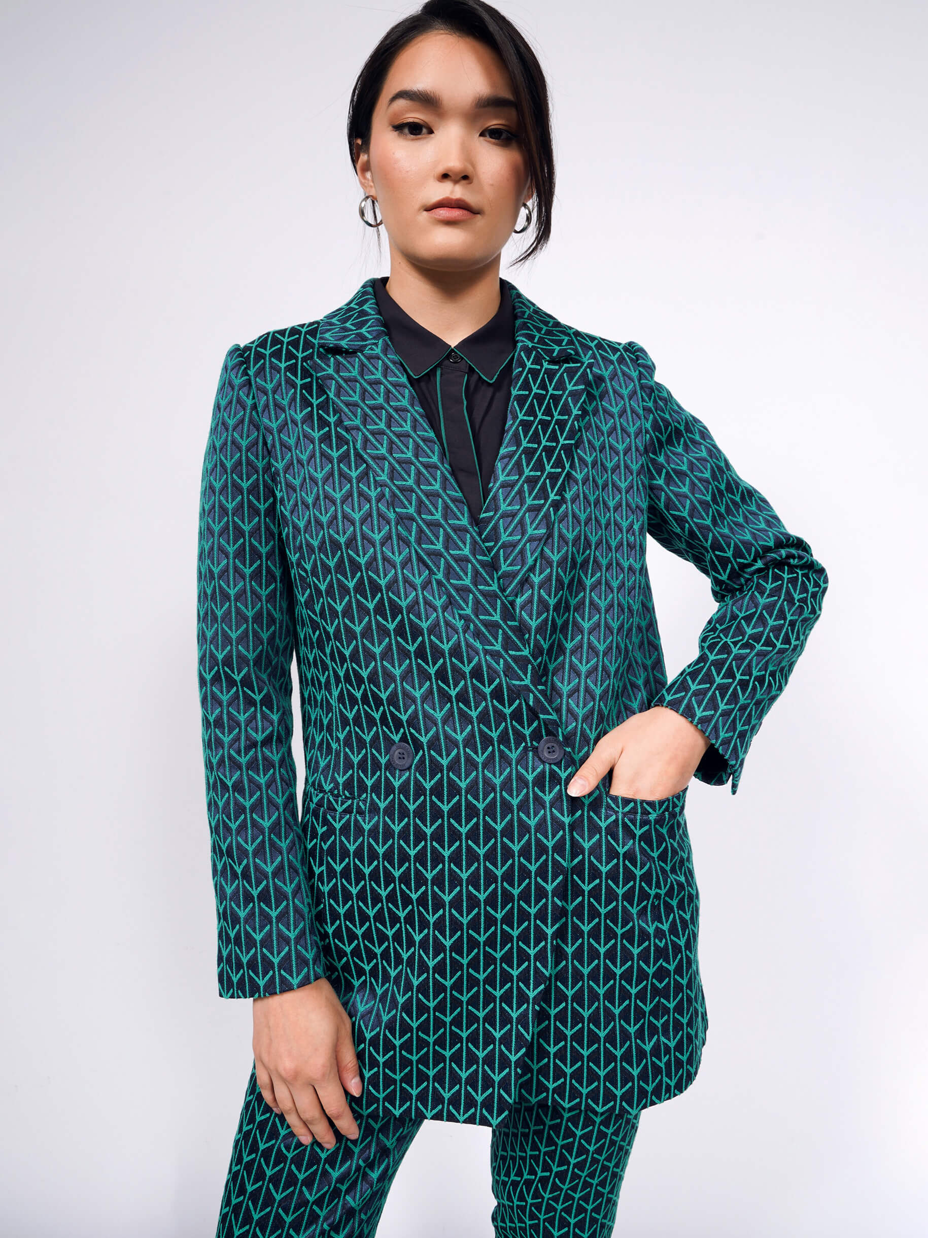 A model wearing a teal and blue patterned blazer suit set. 